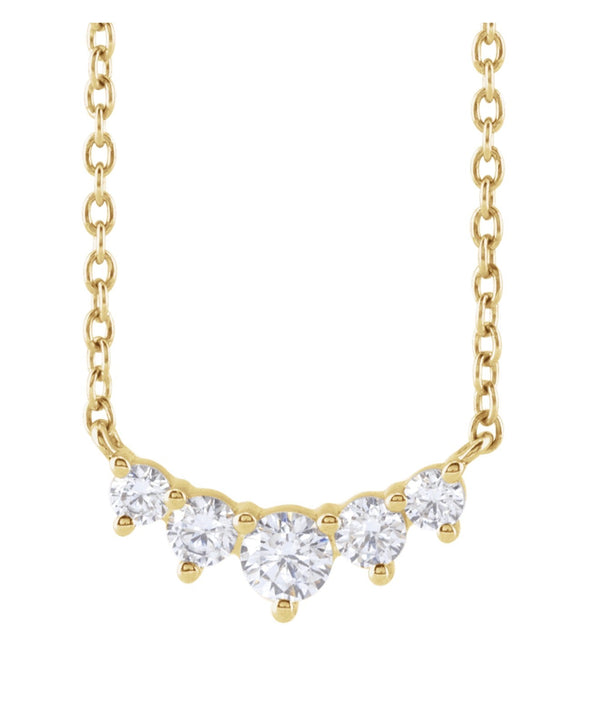 Gold necklace with five graduated diamonds on a white background